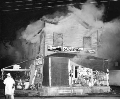 Smoke billows out of a two story wooden structure.